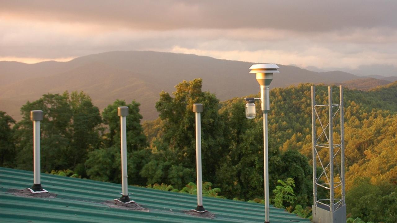 Image: inlet stacks of monitoring station surrounded by forested mountains.
