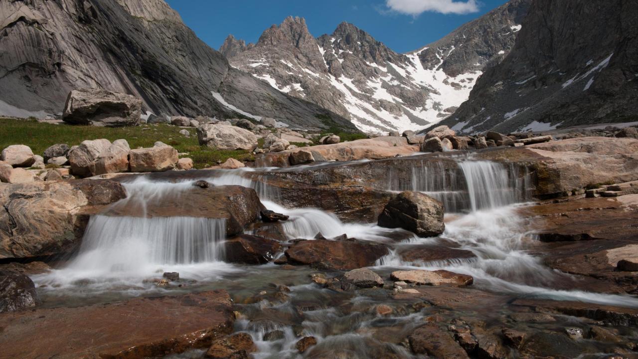 Titcomb Basin Cascade - Photo credit Scott Copeland Image: a photograph of small, rushing falls of water over rocks at Titcomb Basin Cascade.