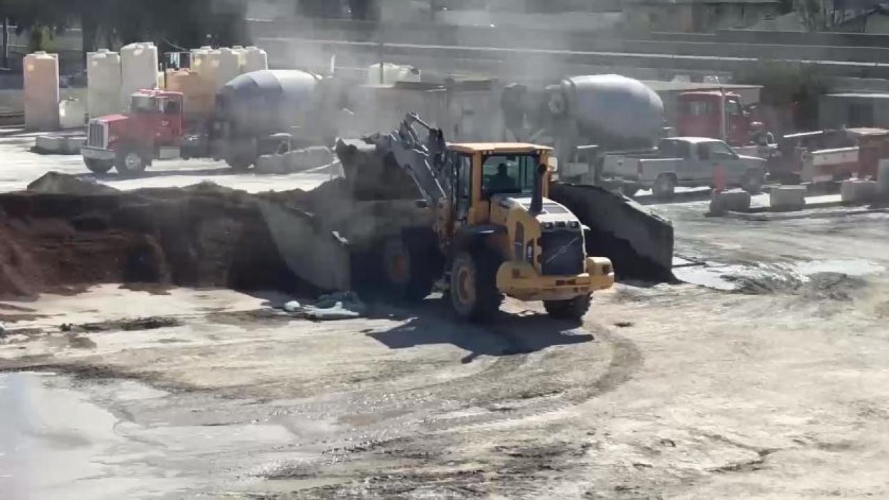 Image: a concrete plant featuring large vehicular equipment and visible dust plumes.