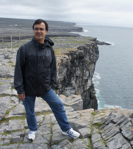 Image: Dr. Ramin Yazdani stands on a rocky sea cliff over water.