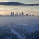 Image: a cityscape enveloped by air pollution.