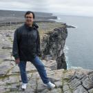 Image: Dr. Ramin Yazdani stands on a rocky sea cliff over water.